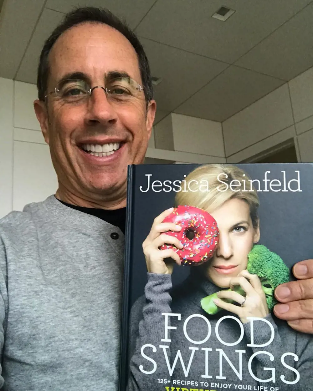 The actor holding his wife, Jessica Seinfeld's, new book titled 